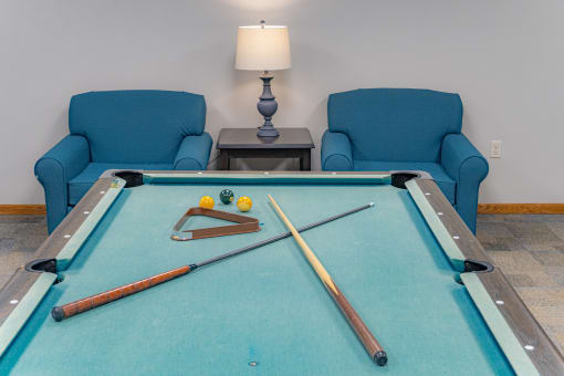 a game room with a pool table and two blue chairs
