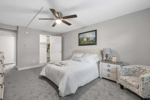 A bedroom with a bed, nightstand, and chair.