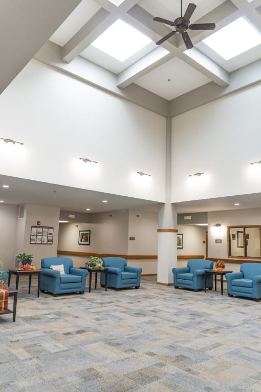 a large lobby with blue couches and chairs and a ceiling fan