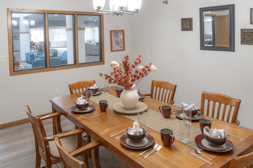 a dining room with a wooden table and chairs and a vase of flowers