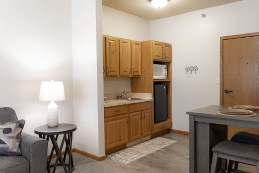 a small living room with a kitchen with a sink and a microwave