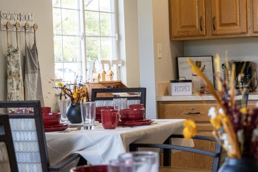 a dining room table with red dishes on it and a window