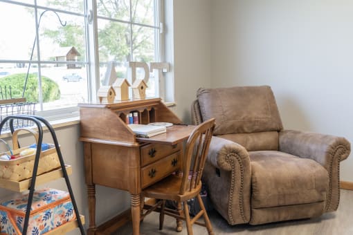 a living room with a chair and a desk and a window