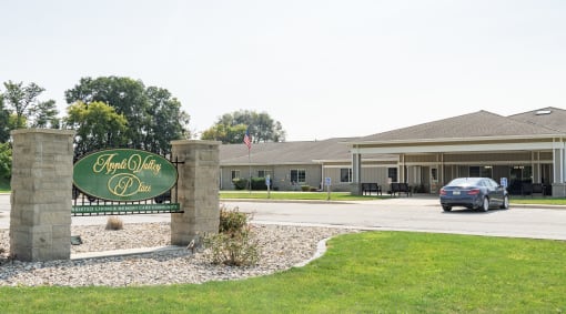 a car drives past the front entrance of a hotel with a green sign