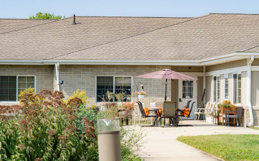 a patio with chairs and an umbrella in front of a house