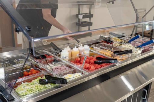 a buffet table with trays of food in a cafeteria