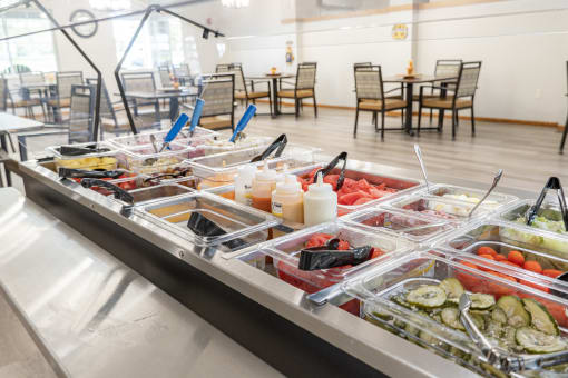 a buffet of food in a cafeteria with tables and chairs