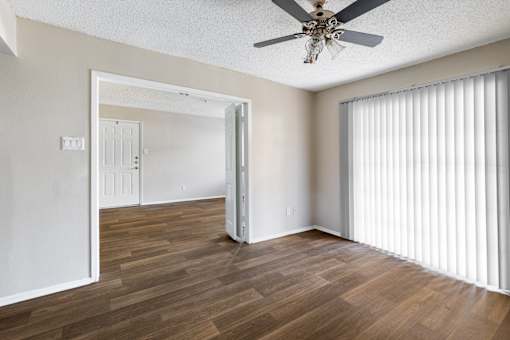 A room with a ceiling fan and wooden flooring.