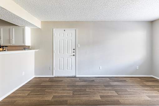 A room with a white door and wooden flooring.