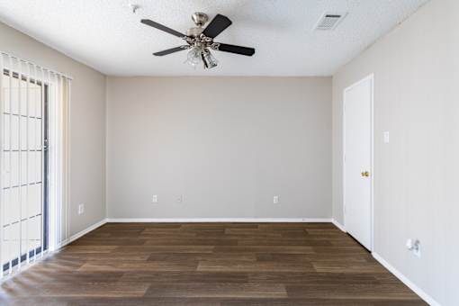 A room with a ceiling fan and wooden flooring.