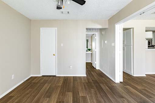 A room with a white door and a brown floor.