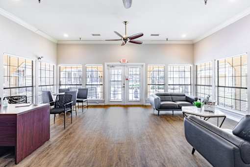 A living room with a grey couch, a wooden floor, and a ceiling fan.