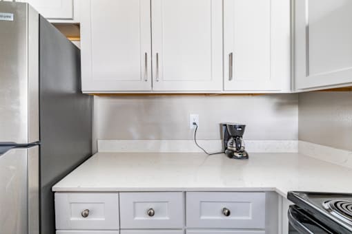 A kitchen with a refrigerator, a coffee maker, and a stove.