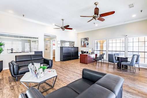 A living room with black leather furniture and a ceiling fan.