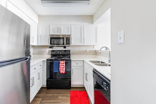 A kitchen with white cabinets and a red rug on the floor.