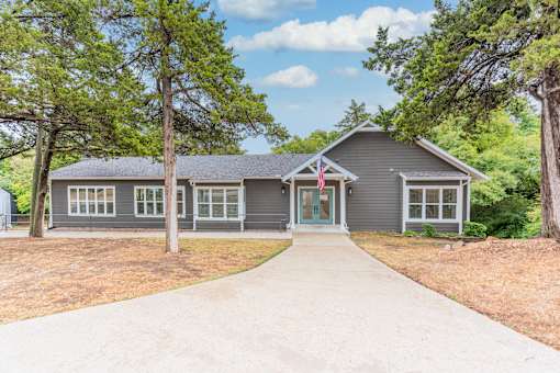 the front of a house with a driveway and trees