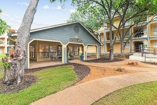 A tree is in front of a building with a sign that says "Leasing Office".