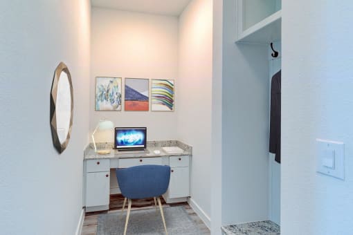a desk with a computer and a chair in a room