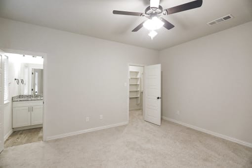 an empty bedroom with a ceiling fan and a closet