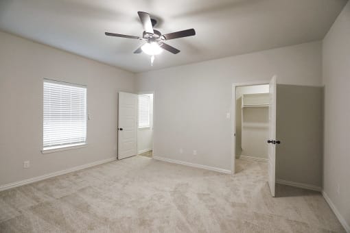 an empty bedroom with a ceiling fan and a closet