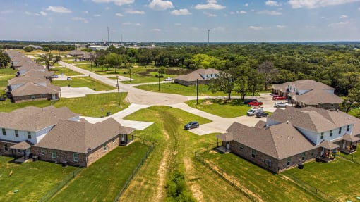 an aerial view of a neighborhood of houses with cars and trees