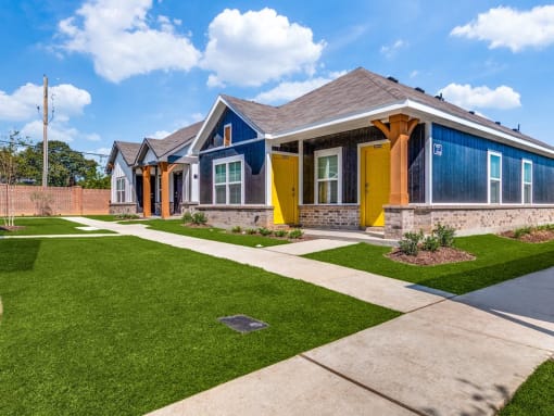 a row of houses with blue and yellow doors and a sidewalk