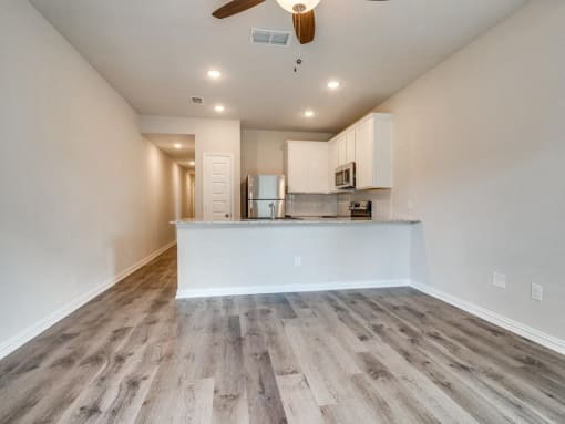 the living room and kitchen of a new home with wood flooring