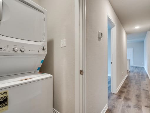 a laundry room with a washer and dryer and a hallway with a door