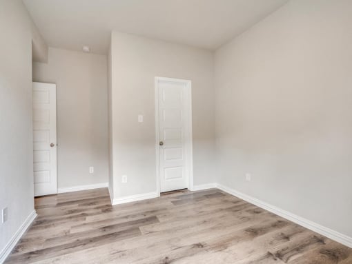 the living room of a home with a white door and wood flooring
