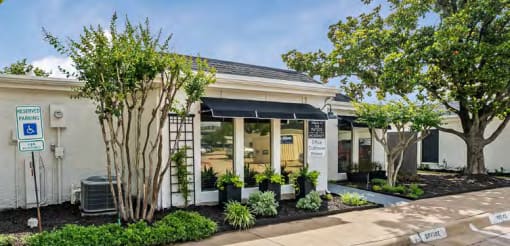 a white building with trees and plants in front of it