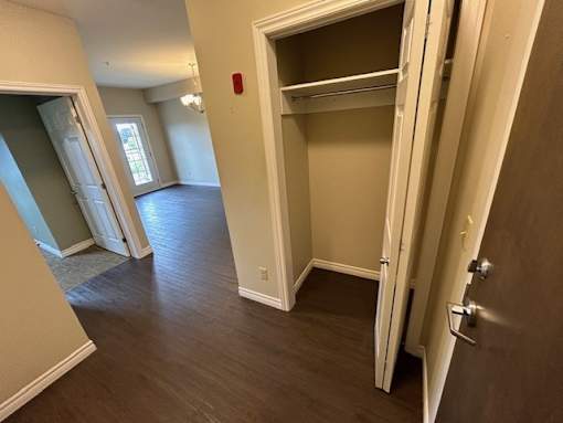 A room with a white door and a brown floor.