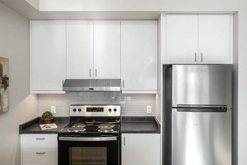 A modern kitchen with a stainless steel refrigerator, oven, and cabinets.