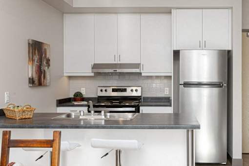 A kitchen with white cabinets and a stainless steel refrigerator.