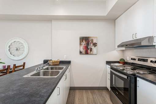 A kitchen with a black countertop and white cabinets.