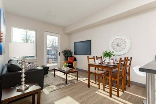 A living room with a black couch, a wooden dining table, and a television.