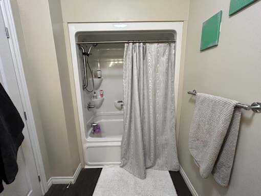 A bathroom with a white shower curtain and a white rug.