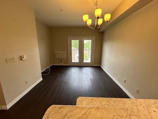 A room with a chandelier, a window, and a door leading outside.