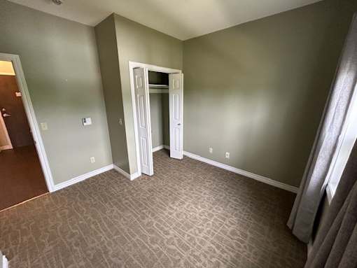 A room with a carpeted floor and a doorway leading to another room.