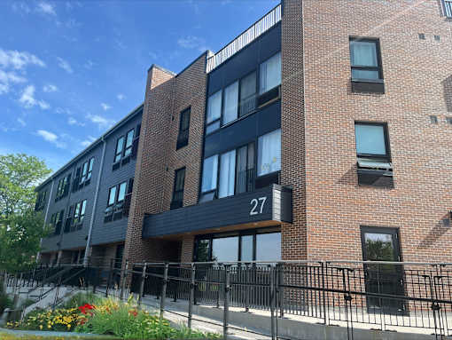 a brick apartment building with a black railing and a gate