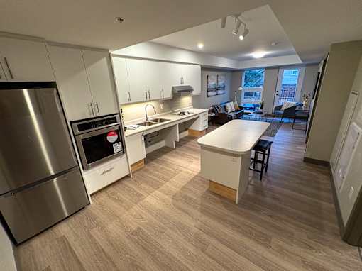 A modern kitchen with a refrigerator, oven, and sink.