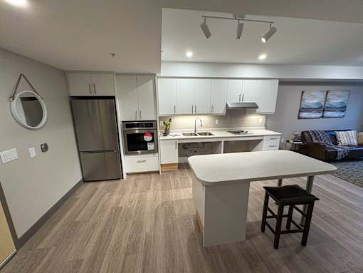 A modern kitchen with a white island and wooden flooring.