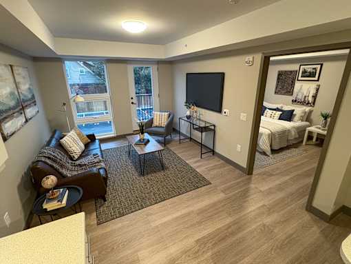 A living room with a brown couch and a television on the wall.
