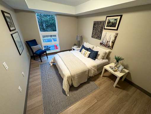 A bedroom with a bed, chair, and pictures on the wall.