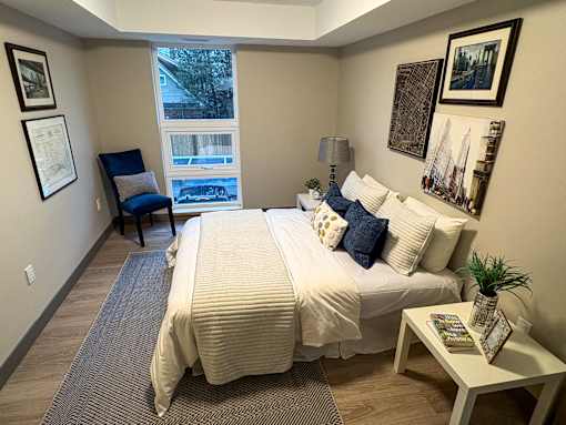 A bedroom with a large bed and a chair.