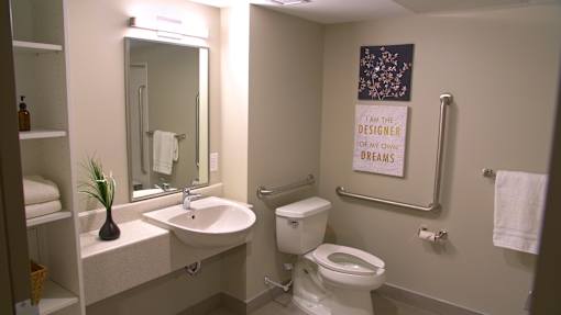 A bathroom with a toilet, sink, mirror and a sign on the wall.