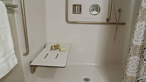 A white bathroom with a white tub and a white towel hanging on the door.