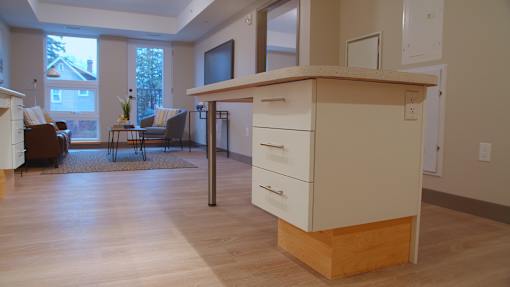 A kitchen with a white counter and a brown chair.