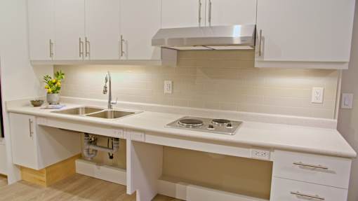 A kitchen with white cabinets and a beige backsplash.