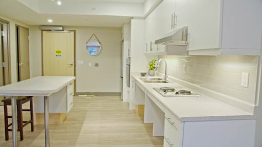 A kitchen with white cabinets and a wooden floor.