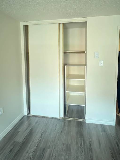A white door with a shelf is open in a room.